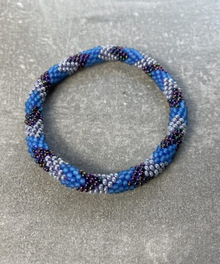 Unikke håndlavet nepal armbånd af glasperler- Som er knyttet perle for perle – Af Nepalesiske Kvinder.  Kvindegrupper i Nepal, Kathmandu Valley, udstyres med glasperler og bomuldsgarn, så de i deres fritid kan håndknytte de smukke perlearmbånd. Hvert armbånd er et unikt resultat af kvindernes håndarbejde og varierer i farvekombinationer og mønstre. De er hæklet med en bomuldssnor. Syntes man at de lidt stramme, kan man vride forsigtigt i dem så de bliver større. syntes man derimod at de er blive lidt for løse, kan man ligge dem i vand. dette gør at bomuldssnoren trækker sig sammen og de bliver mindre igen. Unikke håndlavet nepal armbånd, som er knyttet perle for perle, af nepalesiske kvinder. Vi har mere end 200 forskellige, at vælge i mellem. Så du kan finde de helt rigtige roll on nepal perle armbånd.