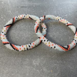 Unikke håndlavet nepal armbånd af glasperler- Som er knyttet perle for perle – Af Nepalesiske Kvinder.  Kvindegrupper i Nepal, Kathmandu Valley, udstyres med glasperler og bomuldsgarn, så de i deres fritid kan håndknytte de smukke perlearmbånd. Hvert armbånd er et unikt resultat af kvindernes håndarbejde og varierer i farvekombinationer og mønstre. De er hæklet med en bomuldssnor. Syntes man at de lidt stramme, kan man vride forsigtigt i dem så de bliver større. syntes man derimod at de er blive lidt for løse, kan man ligge dem i vand. dette gør at bomuldssnoren trækker sig sammen og de bliver mindre igen. Unikke håndlavet nepal armbånd, som er knyttet perle for perle, af nepalesiske kvinder. Vi har mere end 200 forskellige, at vælge i mellem. Så du kan finde de helt rigtige roll on nepal perle armbånd.