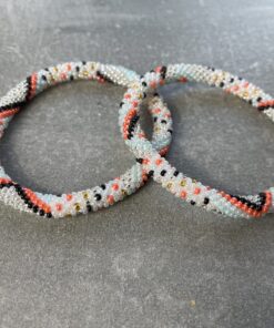 Unikke håndlavet nepal armbånd af glasperler- Som er knyttet perle for perle – Af Nepalesiske Kvinder. Kvindegrupper i Nepal, Kathmandu Valley, udstyres med glasperler og bomuldsgarn, så de i deres fritid kan håndknytte de smukke perlearmbånd. Hvert armbånd er et unikt resultat af kvindernes håndarbejde og varierer i farvekombinationer og mønstre. De er hæklet med en bomuldssnor. Syntes man at de lidt stramme, kan man vride forsigtigt i dem så de bliver større. syntes man derimod at de er blive lidt for løse, kan man ligge dem i vand. dette gør at bomuldssnoren trækker sig sammen og de bliver mindre igen. Unikke håndlavet nepal armbånd, som er knyttet perle for perle, af nepalesiske kvinder. Vi har mere end 200 forskellige, at vælge i mellem. Så du kan finde de helt rigtige roll on nepal perle armbånd.