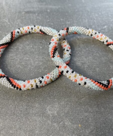 Unikke håndlavet nepal armbånd af glasperler- Som er knyttet perle for perle – Af Nepalesiske Kvinder.  Kvindegrupper i Nepal, Kathmandu Valley, udstyres med glasperler og bomuldsgarn, så de i deres fritid kan håndknytte de smukke perlearmbånd. Hvert armbånd er et unikt resultat af kvindernes håndarbejde og varierer i farvekombinationer og mønstre. De er hæklet med en bomuldssnor. Syntes man at de lidt stramme, kan man vride forsigtigt i dem så de bliver større. syntes man derimod at de er blive lidt for løse, kan man ligge dem i vand. dette gør at bomuldssnoren trækker sig sammen og de bliver mindre igen. Unikke håndlavet nepal armbånd, som er knyttet perle for perle, af nepalesiske kvinder. Vi har mere end 200 forskellige, at vælge i mellem. Så du kan finde de helt rigtige roll on nepal perle armbånd.