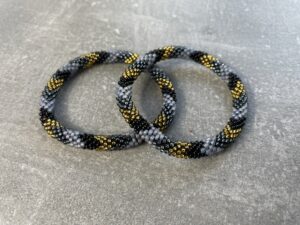Unikke håndlavet nepal armbånd af glasperler- Som er knyttet perle for perle – Af Nepalesiske Kvinder.  Kvindegrupper i Nepal, Kathmandu Valley, udstyres med glasperler og bomuldsgarn, så de i deres fritid kan håndknytte de smukke perlearmbånd. Hvert armbånd er et unikt resultat af kvindernes håndarbejde og varierer i farvekombinationer og mønstre. De er hæklet med en bomuldssnor. Syntes man at de lidt stramme, kan man vride forsigtigt i dem så de bliver større. syntes man derimod at de er blive lidt for løse, kan man ligge dem i vand. dette gør at bomuldssnoren trækker sig sammen og de bliver mindre igen. Unikke håndlavet nepal armbånd, som er knyttet perle for perle, af nepalesiske kvinder. Vi har mere end 200 forskellige, at vælge i mellem. Så du kan finde de helt rigtige roll on nepal perle armbånd.