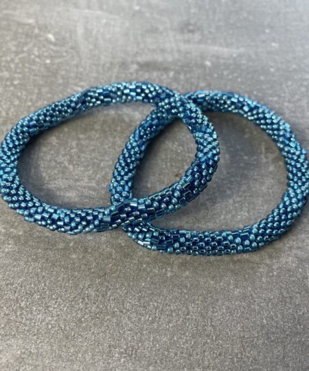 Unikke håndlavet nepal armbånd af glasperler- Som er knyttet perle for perle – Af Nepalesiske Kvinder.  Kvindegrupper i Nepal, Kathmandu Valley, udstyres med glasperler og bomuldsgarn, så de i deres fritid kan håndknytte de smukke perlearmbånd. Hvert armbånd er et unikt resultat af kvindernes håndarbejde og varierer i farvekombinationer og mønstre. De er hæklet med en bomuldssnor. Syntes man at de lidt stramme, kan man vride forsigtigt i dem så de bliver større. syntes man derimod at de er blive lidt for løse, kan man ligge dem i vand. dette gør at bomuldssnoren trækker sig sammen og de bliver mindre igen. Unikke håndlavet nepal armbånd, som er knyttet perle for perle, af nepalesiske kvinder. Vi har mere end 200 forskellige, at vælge i mellem. Så du kan finde de helt rigtige roll on nepal perle armbånd.